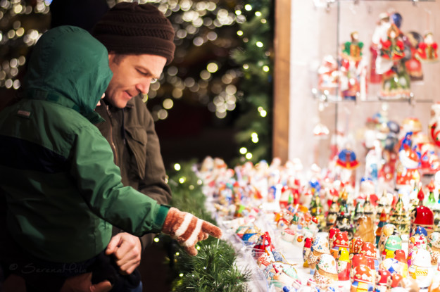 child being held by adult points at Christmas decorations