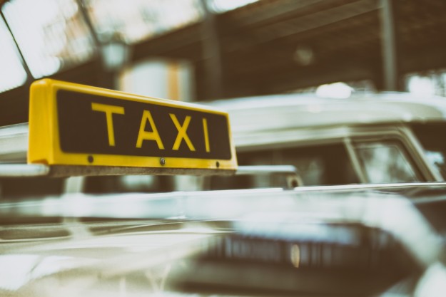 A taxi cab showing a taxi sign on the roof