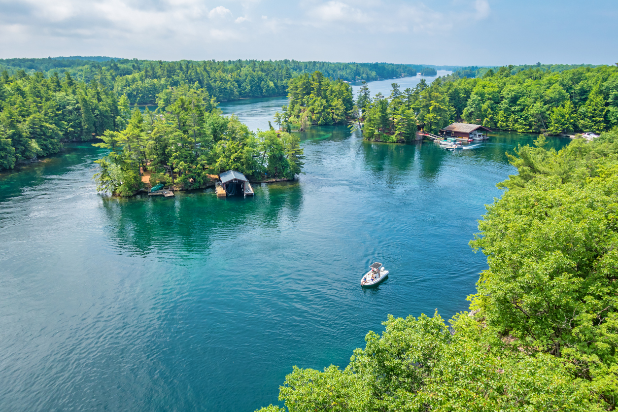 Boast drift between boathouses on the the crystal blue waters of Thousand Islands National Park